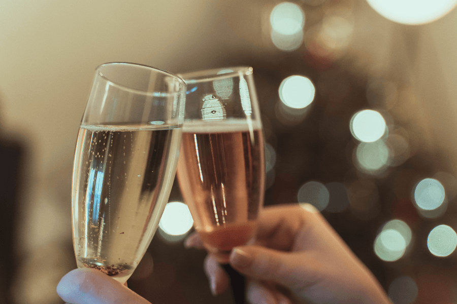 Two champagne flutes clink together against a softly lit background.